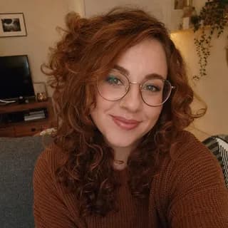 Example selfie of a woman with red curls and glasses on a sofa